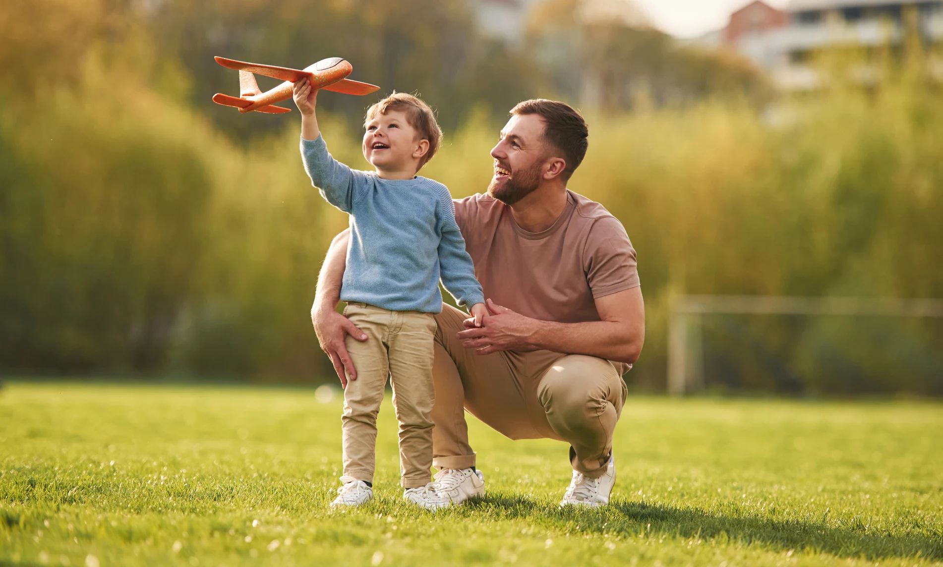 Dad with minimum essential coverage plays with his son outside.